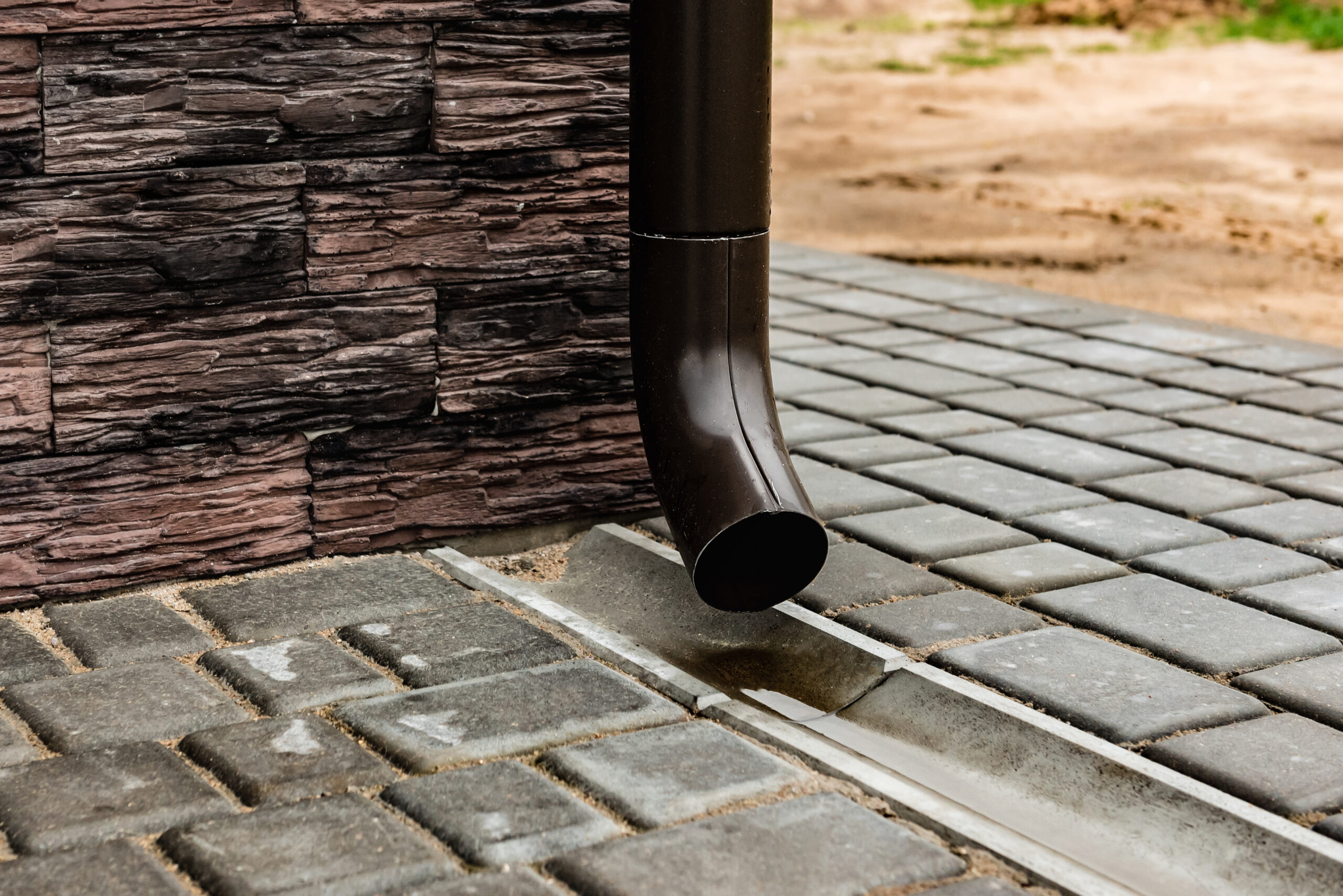 Drain pipe on the brown brick wall. Downspout.